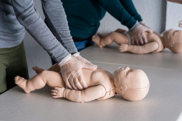 A person is performing cpr on an infant dummy.