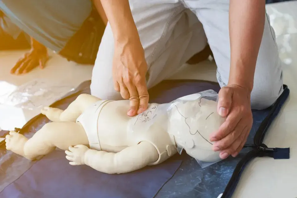 A person is performing cpr on an infant.